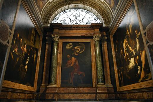 Intérieur de chapelle orné de grandes peintures religieuses encadrées de marbre et de colonnes.