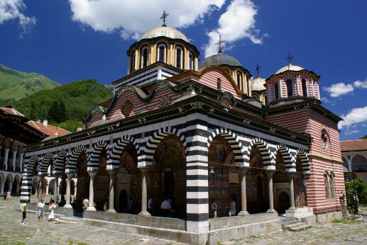 Vue extérieure de l'église de la Nativité de la Vierge du monastère de Rila, avec ses arcades peintes et ses coupoles.