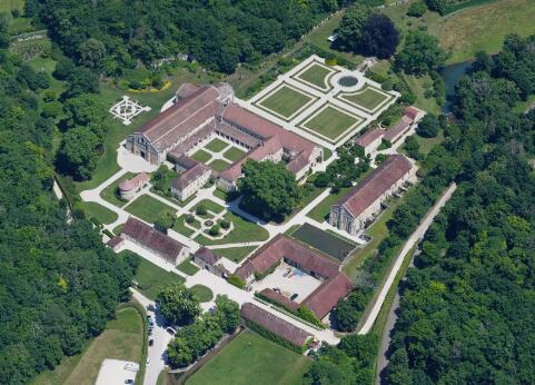 Vue aérienne d'une abbaye cistercienne entourée de jardins géométriques et de bâtiments conventuels.