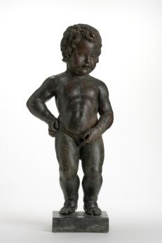 Statue en bronze d'un enfant nu debout sur un socle, sur fond clair.