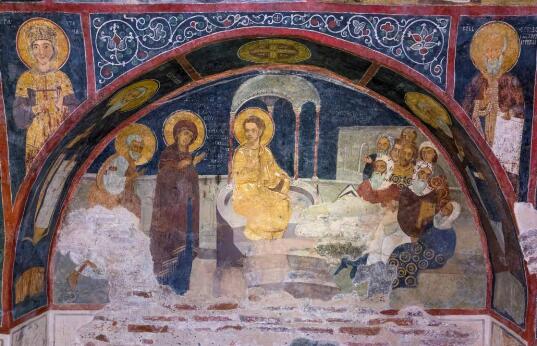 Fresque murale représentant une scène religieuse avec le Christ entouré de personnages auréolés sous une arcade peinte.