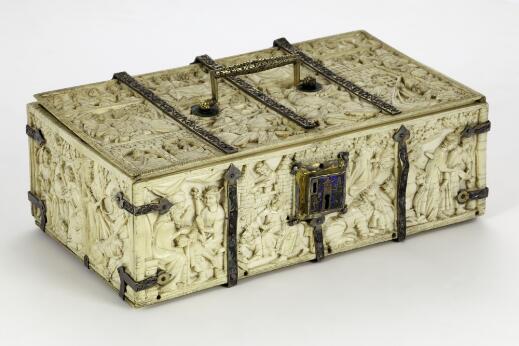 Coffret rectangulaire en ivoire sculpté de scènes figurées en bas-relief, renforcé par des ferrures métalliques et muni d'une poignée et d'une serrure ornée, présenté sur fond neutre.