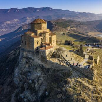 Église à plan centré surmontée d'un dôme, construite en pierre et implantée au sommet d'un promontoire rocheux fortifié, vue aérienne dans un paysage montagneux.