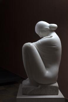 Sculpture blanche représentant une figure humaine assise