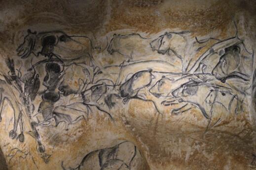 Peinture pariétale préhistorique représentant un groupe de lions poursuivant des bisons et d'autres animaux.