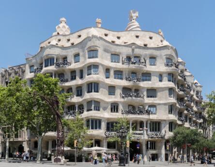 Façade ondulante d'un immeuble moderniste en pierre sculptée avec balcons en fer forgé.