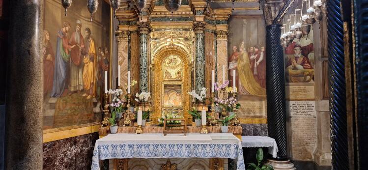 Chapelle ornée d'un autel en marbre et dorures, abritant une icône mariale entourée de peintures murales et de colonnes.