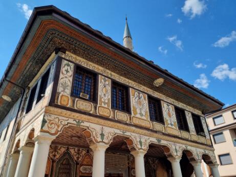 Façade d'une mosquée ottomane richement décorée de peintures florales et géométriques, portée par un portique à colonnes.