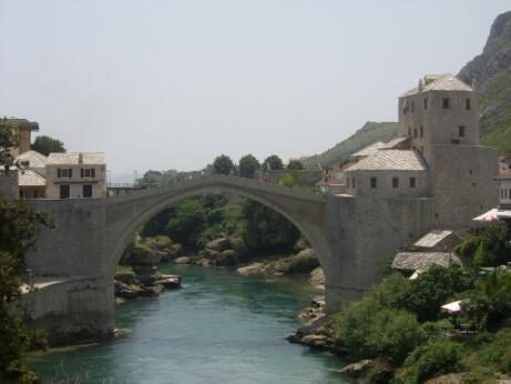 Photographie représentant un pont en pierre enjambant une rivière entre deux tours fortifiées.