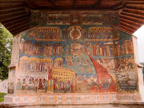 Fresque monumentale représentant le Jugement dernier, organisée en registres superposés avec le Christ, des saints, des anges, les élus et les damnés, peinte sur la façade extérieure d'une église orthodoxe.