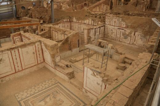 Vue des vestiges de maisons romaines antiques ornées de fresques murales et de mosaïques, conservées dans un vaste complexe archéologique.