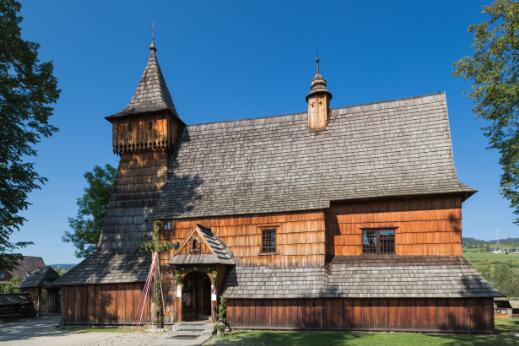Vue extérieure d'une église en bois à clocher, caractéristique de l'architecture religieuse traditionnelle d'Europe centrale.