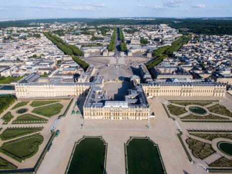 Vue aérienne représentant le château de Versailles, ses cours et ses jardins à la française, prolongés par de larges perspectives paysagères.