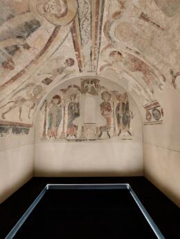Photographie représentant un espace voûté orné de fresques médiévales à caractère religieux.