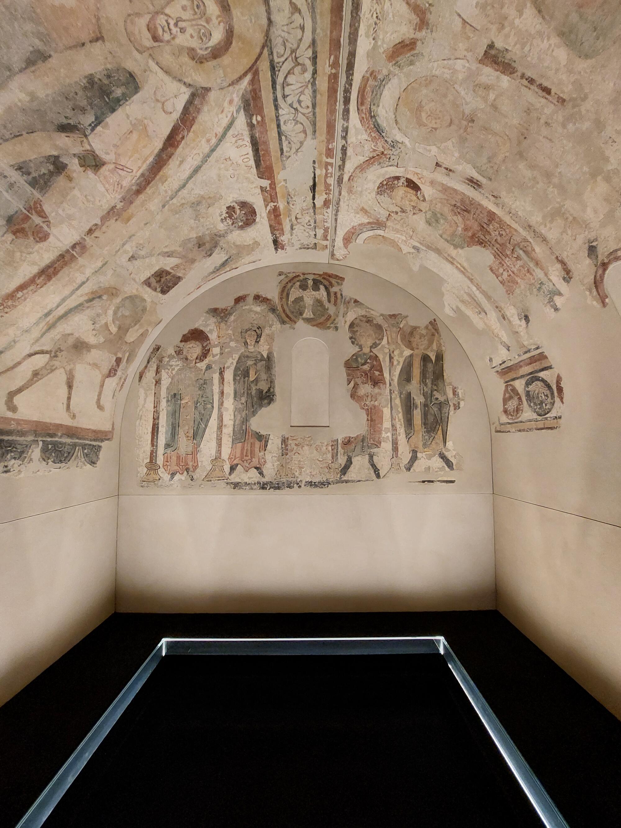 Preview of: Absid Frescoes in the Santa Coloma church Photographie représentant un espace voûté orné de fresques médiévales à caractère religieux.