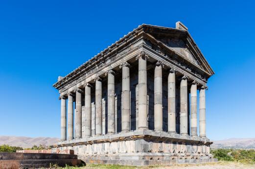 Vue extérieure d'un temple gréco-romain périptère, élevé sur un podium et entouré de colonnes corinthiennes.