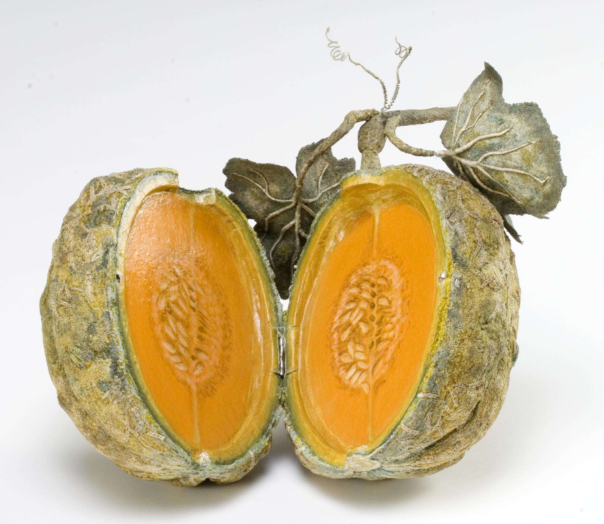 Preview of: Embroidered melon Melon ouvert en deux montrant sa chair orange et ses graines, avec feuilles et tiges attachées, sur fond clair.