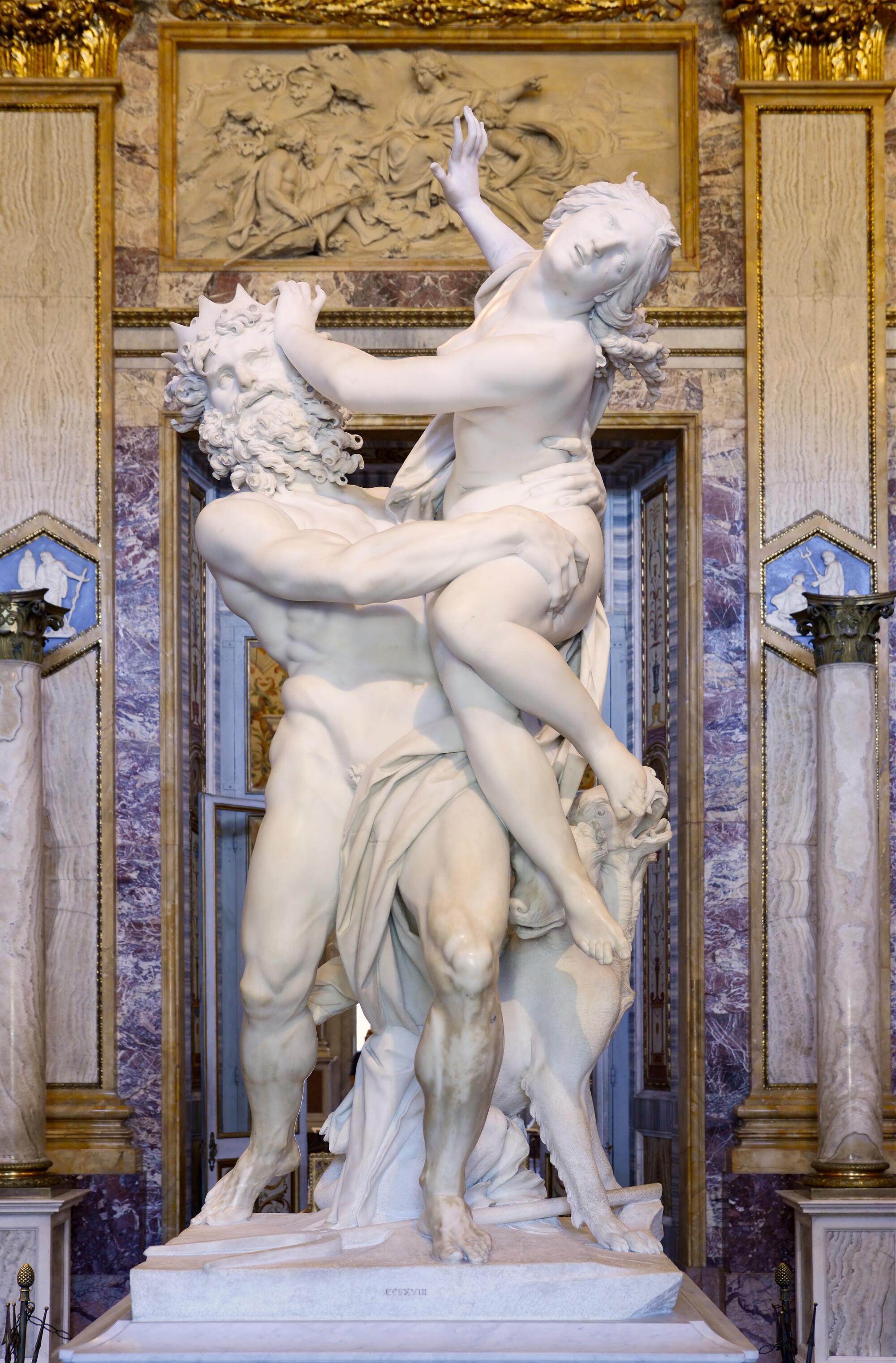 Preview of: The Rape of Proserpina Sculpture en marbre représentant deux figures humaines enlacées dans une composition dynamique, exposée dans un intérieur richement décoré de colonnes et reliefs.