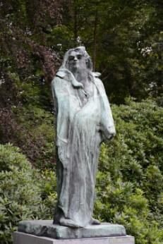 Photographie montrant une sculpture monumentale représentant un homme drapé, installée dans un jardin.
