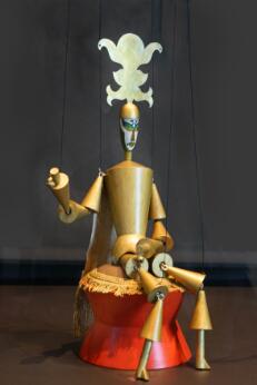 Marionnette représentant un personnage couronné stylisé, réalisée en bois peint avec des membres articulés et suspendue par des fils.