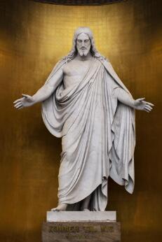 Sculpture religieuse représentant le Christ ressuscité debout, les bras ouverts dans un geste d'accueil et de bénédiction.