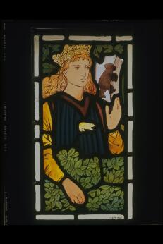 Personnage couronné représenté dans un vitrail, entouré de feuillages et d’un petit animal.